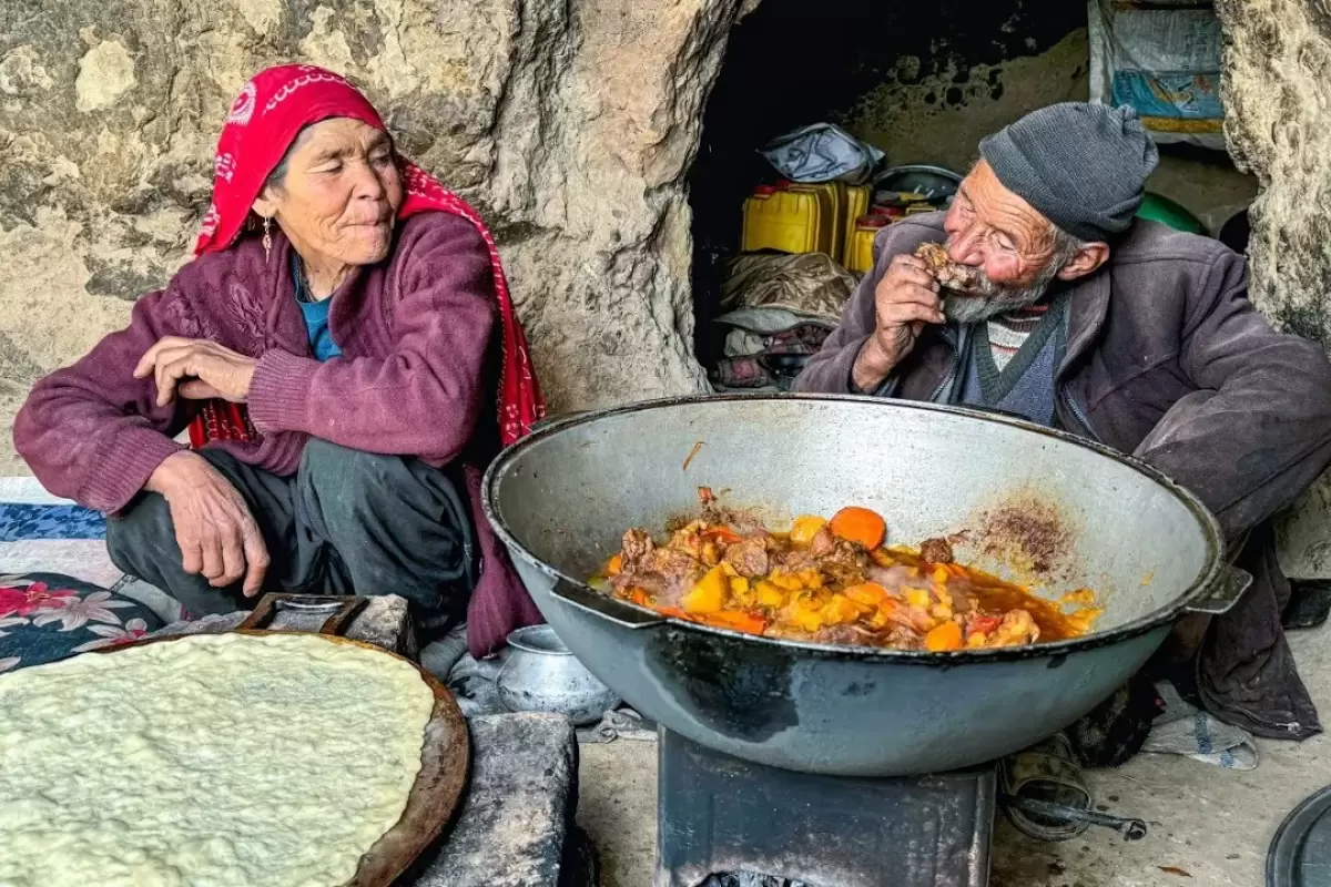 (ویدئو) پخت نان ساجی و یک غذای محلی با ران گوسفند توسط زوج غارنشین افغانستانی