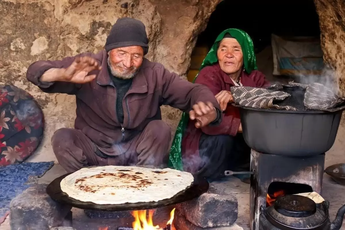 (ویدئو) پخت نان ساجی و دمپخت مرغ توسط یک زوج مسن غارنشین افغان