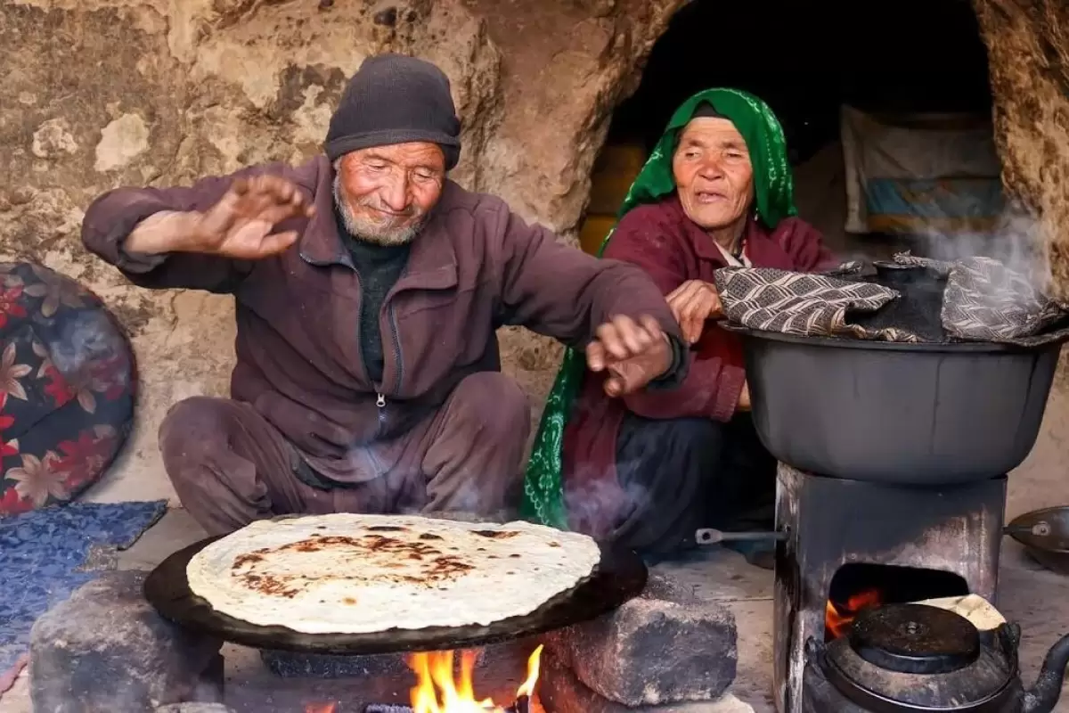 (ویدئو) روش دیدنی پخت نان ساجی و املت زغالی توسط یک زوج جوان غارنشین افغان