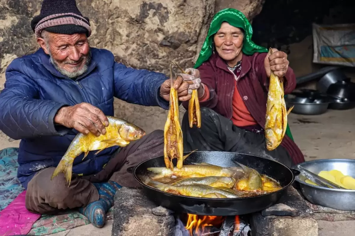 (ویدئو) روش دیدنی یک زوج غارنشین افغان در پخت یک غذای محلی با ماهی