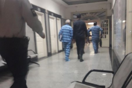 حسین هدایتی با دستبند و ماسک در راهرو دادگاه کیفری تهران